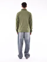 Buzo de polar color verde oliva, con cuello alto y cierre frontal parcial. Presenta puños y cintura acanalados.