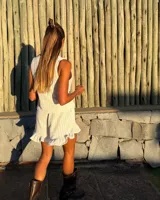 Blusa sin mangas color blanco, tejida con textura acanalada y escote pronunciado en V, sujeta en el centro con dos apliques metálicos con forma de sol.