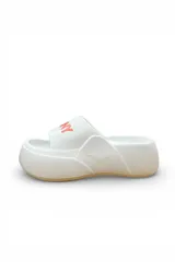 Chancletas blancas de plataforma con faja ancha y suela de goma. Tienen detalles en color salmón en la faja y suela tostada.