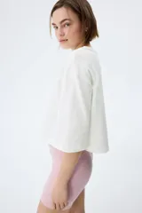 Remera oversized confeccionada en punto de algodón suave, de corte boxy con cuello redondo, hombros caídos y media manga.