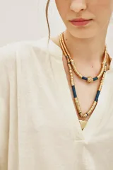 Remera de algodón color crudo, con cuello en V y mangas largas. Presenta un diseño holgado con puños tejidos y detalle de costura central en el escote.