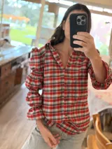 Camisa de manga larga con estampado de cuadros en tonos rojos, blancos y azules. Presenta un diseño con mangas abullonadas divididas por secciones elásticas y cierre frontal con botones.