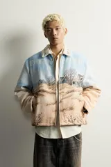 Cazadora relaxed fit de tejido jacquard ligeramente acolchado, con estampado de paisaje costero y texto "Un dernier souffle d'été". Cuenta con cuello solapa con inscripción, manga larga, bolsillos de vivo en la cadera y cierre frontal con cremallera.