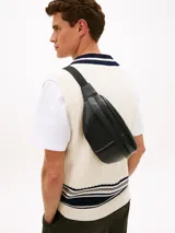 Riñonera Tommy Hilfiger de estilo urbano, color negro, confeccionada en mezcla de algodón y poliéster. Cuenta con correa ajustable con broche, compartimento principal con cierre, detalle de franja tricolor central y logo metalizado de la marca.