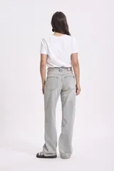 Pantalón de jean celeste de corte ancho, con detalles de ojalillos metálicos en la parte delantera.