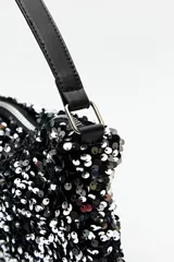 Cartera tipo baguette color negro cubierta de lentejuelas plateadas.