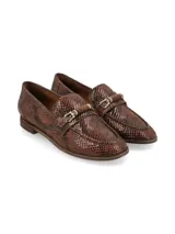 Mocasín de cuero con estampado de imitación piel de reptil en tonos marrones, con detalle de estribo metálico dorado en el empeine y suela plana.