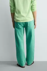 Jeans de mezclilla de corte recto, tiro medio, color verde vibrante con efecto lavado. Presenta cierre frontal con cremallera y botón, y cinco bolsillos.