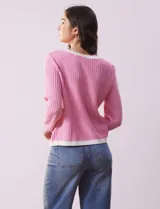 Cardigan de tejido tweed celeste y blanco, con escote redondo, cierre frontal con botones metálicos dorados y bolsillos simulados en el frente.