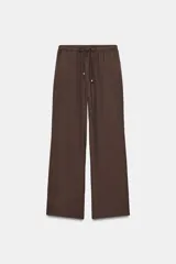 Pantalón ancho de tiro alto color marrón oscuro, con cintura elástica ajustable mediante cordones con terminales doradas. Presenta textura arrugada en la tela y bolsillos laterales.