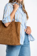 Camisa de corte oversize con estampado de rayas verticales en tonos azul y beige. Presenta cuello camisero clásico, cierre frontal con botones, bolsillo en el pecho y mangas largas con puños rectos.