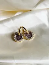 Aros de acero quirúrgico con dije circular de resina rosa y borde de strass dorados.