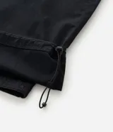 Pantalón cargo de corte mega baggy, color negro, confeccionado en sarga de algodón. Presenta múltiples bolsillos funcionales y un diseño versátil que permite transformar la prenda en bermuda mediante un sistema de ajuste en las piernas.