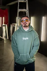 Canguro verde militar con capucha, estampado con texto en el frente y costuras a la vista.