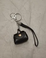 Llavero con dije de mini bolso negro con detalles dorados y correa fina.