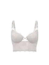 Bralette largo de encaje color blanco con aros, escote pronunciado en V, aberturas entrecruzadas al frente y tirantes brillantes con la marca Victoria's Secret en pedrería.