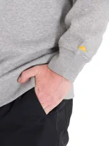 Buzo de cuello redondo color gris melange, con el logotipo de la marca estampado en el pecho en color negro y detalle de pequeño triángulo amarillo bordado en la manga izquierda. Presenta puños y bajo de punto elástico.