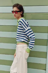 Sweater de punto a rayas horizontales en azul y blanco, con cuello polo verde lima, escote en V y detalles en verde lima en los puños y el borde inferior.