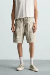 Bermuda relaxed fit confeccionada en tejido de algodón con efecto lavado. Presenta un diseño de cinco bolsillos, bolsillo multifunción en la pernera y tira lateral de estilo carpintero. Cuenta con cierre frontal con cremallera y botón.