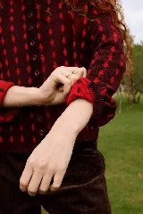 Cardigan reversible de punto con diseño de rombos pequeños, cuello redondo y cierre frontal con botones. Presenta un patrón bicolor en tonos bordó y rojo.