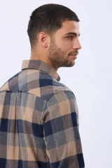 Camisa de viyela a cuadros en tonos marrón, azul marino y gris, con cuello clásico, cierre frontal con botones, mangas largas y un bolsillo en el pecho.