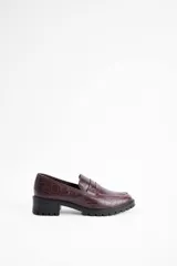 Mocasines negros de estilo clásico con textura de cuero grabado tipo cocodrilo. Presentan una banda frontal característica y suela plana con borde definido.