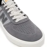 Championes urbanos New Balance modelo NM272LMP, color gris con detalles en negro, confeccionados en gamuza y lona, con logo "N" característico en los laterales y suela blanca.