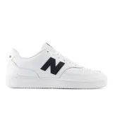 Championes urbanos New Balance modelo 80, color blanco con logo lateral en negro. Diseño de corte bajo con perforaciones en la puntera y suela de goma.