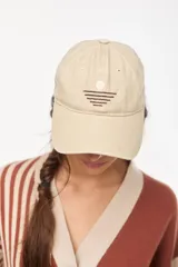 Gorra beige con bordado frontal de un sol y líneas horizontales, visera curva y cierre ajustable.