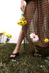 Falda larga recta con caída fluida, pretina tejida en punto elástico y cuerpo inferior tejido en telar con hilos de algodón y poliéster. Presenta un tajo lateral y un patrón de cuadros en tonos rojo, amarillo y negro.