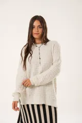 Buzo oversize color beige confeccionado en tejido sintético con destellos de lurex, cuello redondo y manga larga.