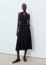 Vestido midi sin mangas, de corte evasé y cuello en pico. Presenta cierre frontal con botones, bolsillos laterales y cinturón ajustable a tono. Confeccionado en mezcla de lyocell y lino, incluye forro interior.