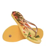 Sandalias tipo ojota Havaianas modelo Slim Tropical, con base amarilla estampada con motivos botánicos y tiras finas en color bronce metalizado.