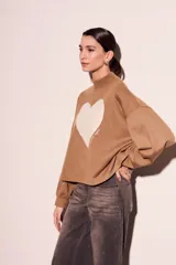 Sweater marrón de algodón peinado con cuello alto y calce oversize. Estampado frontal de corazón blanco con texto en cursiva.