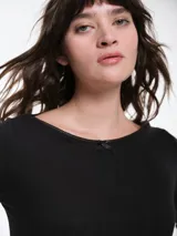 Remera de manga larga entallada en tejido pointelle, con escote bote y detalle de pequeño lazo central. Presenta un acabado con borde picot en el escote.