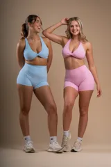 Conjunto deportivo color rosa compuesto por un top halter con detalle cruzado en el frente y shorts de tiro alto.