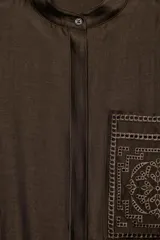 Camisa ZW Collection de color marrón oscuro, con cuello mao, manga larga con puños anchos y cierre frontal oculto por solapa. Cuenta con un bolsillo de parche en el pecho adornado con bordados a tono, los cuales también se repiten en los puños.