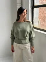 Sweater de punto color verde oliva, con cuello bote y mangas murciélago. Presenta un diseño de textura acanalada vertical en el frente y puños ajustados.