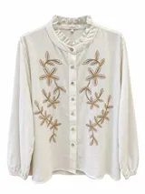 Camisa blanca de manga larga con cuello mao con volados, cierre frontal con botones y bordados florales en tono beige en el frente.