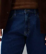 Pantalón de jean corte slim color azul oscuro, con cierre frontal de botón y cremallera, pasadores para cinturón y bolsillos funcionales.