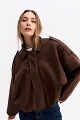 Campera de gamuza sintética color verde oliva, con silueta amplia, hombros caídos y cierre frontal. Presenta un diseño estructurado con volumen en mangas y cuerpo.