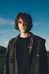 Chaleco de denim negro con efecto deslavado, diseño sin mangas, bolsillos frontales con solapa, costuras en contraste y botones metálicos.