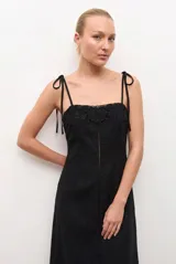Vestido midi negro con tirantes ajustables mediante lazos, escote recto y detalle de encaje bordado en el pecho y en el ruedo.