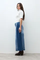 Falda larga de jean de tiro alto, con lavado medio y tajo frontal profundo. Presenta un diseño bicolor con paneles de denim de tonos ligeramente diferentes.