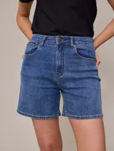 Short de jean elastizado en color azul clásico, con tiro medio, cierre frontal con botón metálico y bolsillos laterales y traseros.