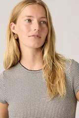 Remera de manga corta con estampado de cuadros vichy en tonos blanco y negro, de ajuste entallado y cuello redondo con detalle de borde festoneado.