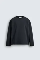 Sudadera de corte relajado confeccionada en algodón compacto con interior de rizo. Presenta cuello redondo acabado en rib, manga larga y bordes irregulares enrollados.