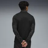 Buzo deportivo Puma del Club Atlético Peñarol, modelo de entrenamiento con cierre frontal de 1/4. Presenta un diseño en tonos negros con estampado sutil, logo de la marca y escudo del club en amarillo.