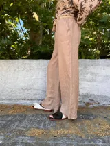 Pantalón de lino color beige, de corte ancho y tiro alto, con cintura elastizada y cinturón de soga.