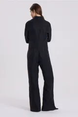 Mono largo negro de corte holgado, con cuello camisero, cierre frontal con cremallera y mangas largas.